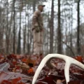 A man standing in the woods with a deer antler